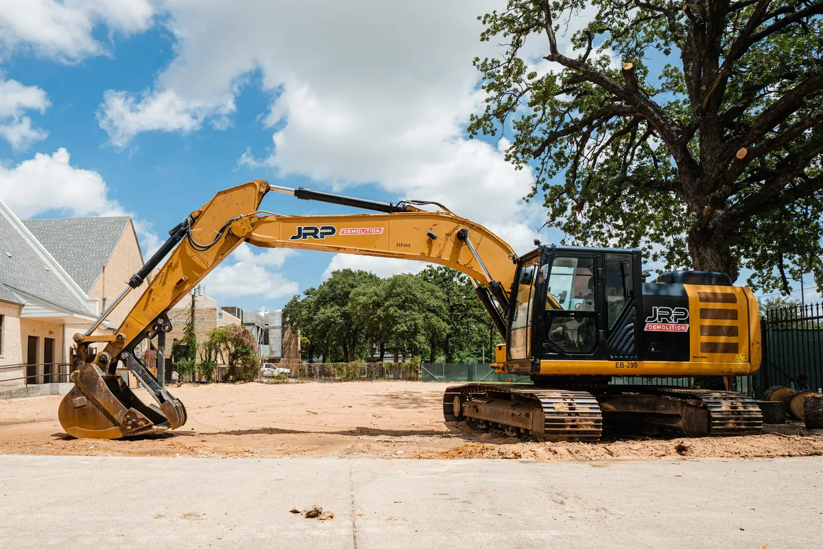 JRP Demolition branded hydraulic excavator on a cleared residential lot in Dallas-Fort Worth with graded soil ready for new construction